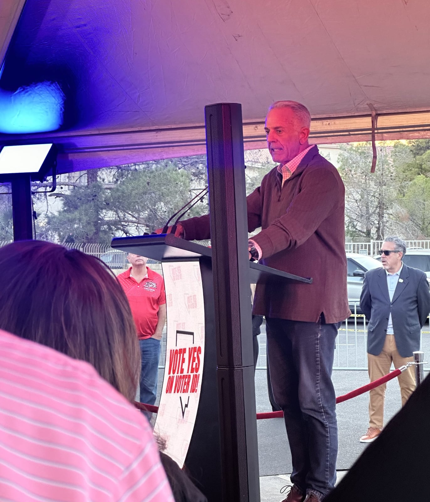Nevada Governor Joe Lombardo speaking at the microphone-equipped lectern under blue and red stage lighting